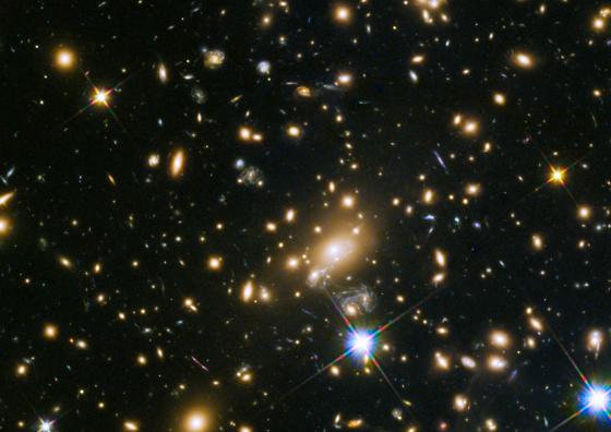 This image shows the huge galaxy cluster MACS J1149.5+223, whose light took over 5 billion years to reach us.  The huge mass of the cluster is bending the light from more distant objects. The light from these objects has been magnified and distorted due to gravitational lensing. The same effect is creating multiple images of the same distant objects.